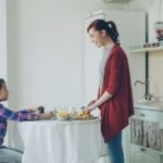 Mother serving her young daughter breakfast at the table